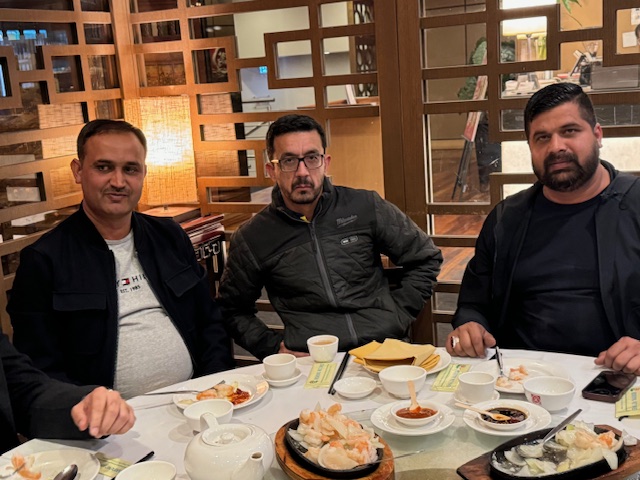 A group of men sitting at a table with food
Description automatically generated