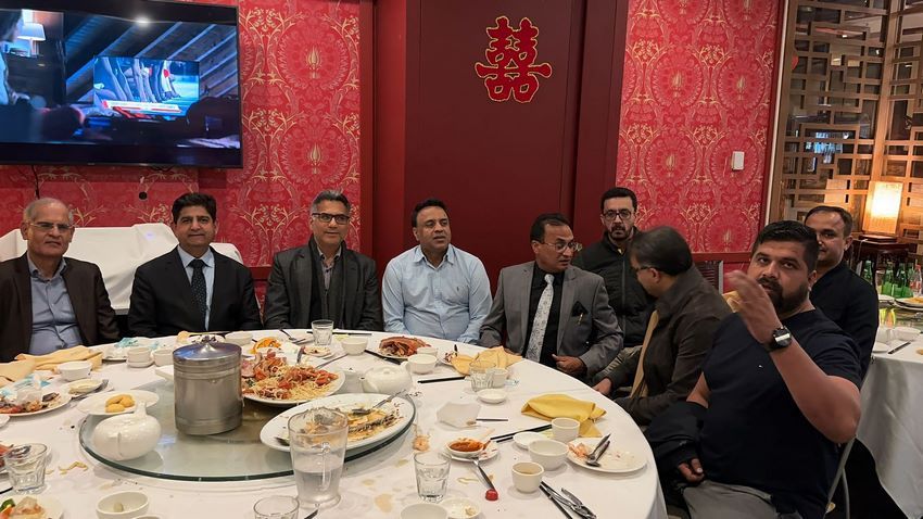 A group of men sitting around a table with food
Description automatically generated