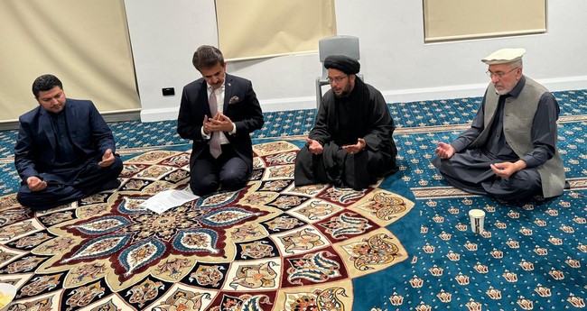 Two men sitting on a rug
Description automatically generated