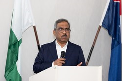 A person standing at a podium holding a microphone

Description automatically generated