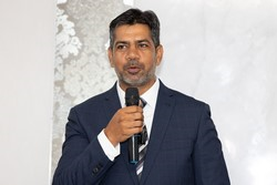A person in a suit holding a microphone

Description automatically generated