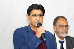 A person in a blue suit holding a microphone

Description automatically generated