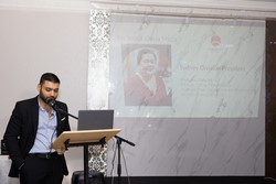 A person standing at a podium speaking into a microphone

Description automatically generated