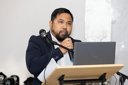 A person speaking into a microphone

Description automatically generated