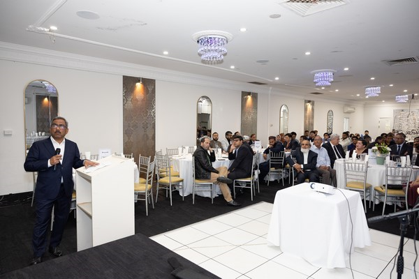 A person standing at a podium in front of a group of people
Description automatically generated