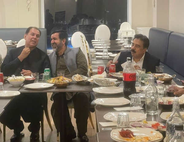 A group of men sitting at a table with food

Description automatically generated