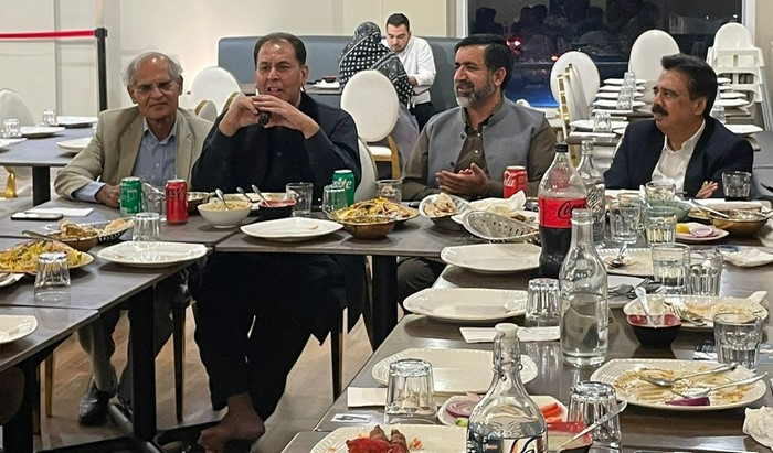 A group of men sitting at a table with plates and food

Description automatically generated