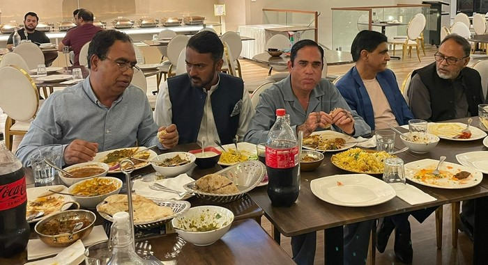 A group of men sitting at a table with food

Description automatically generated