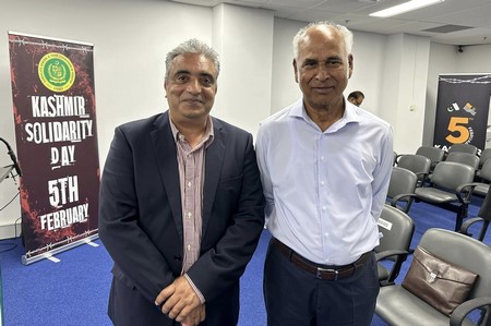 Two men standing in a room
Description automatically generated