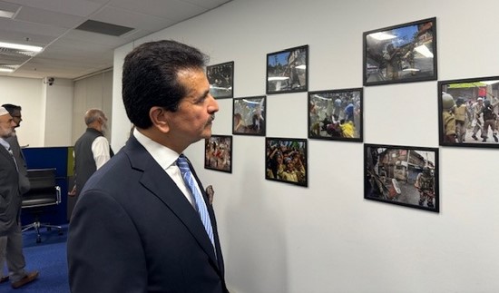 A person in a suit looking at a wall of pictures
Description automatically generated