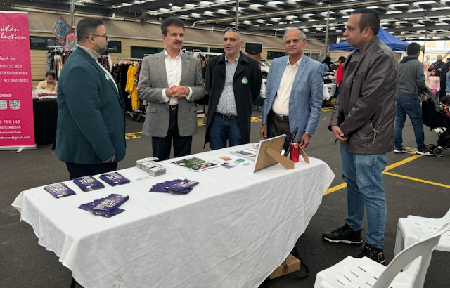 A group of men standing around a table
Description automatically generated