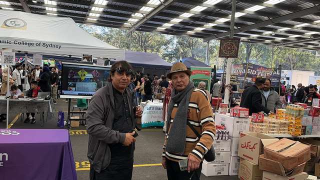A group of men standing in a market
Description automatically generated