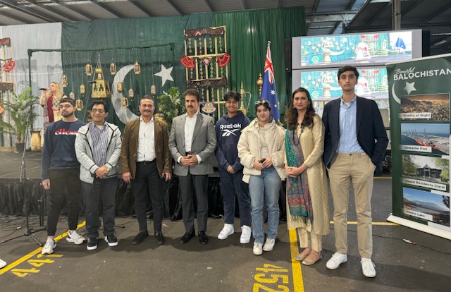 A group of people standing in front of a green wall
Description automatically generated