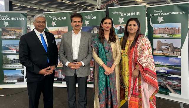 A group of people standing in front of a green banner
Description automatically generated