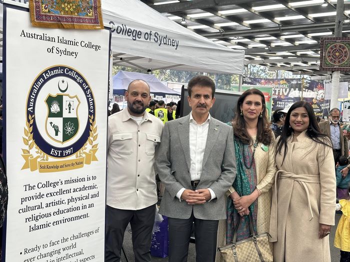 A group of people standing in front of a sign
Description automatically generated