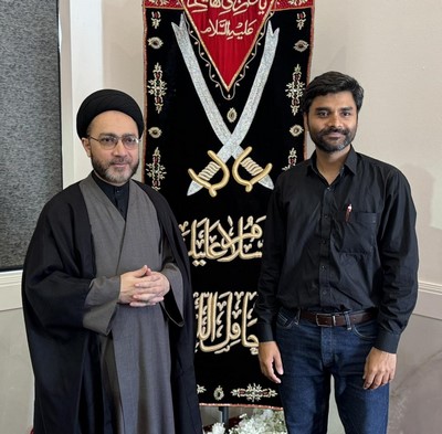 Two men standing in front of a banner
Description automatically generated