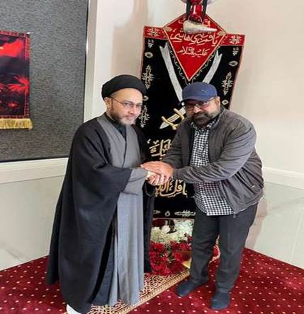 Two men shaking hands in a room
Description automatically generated