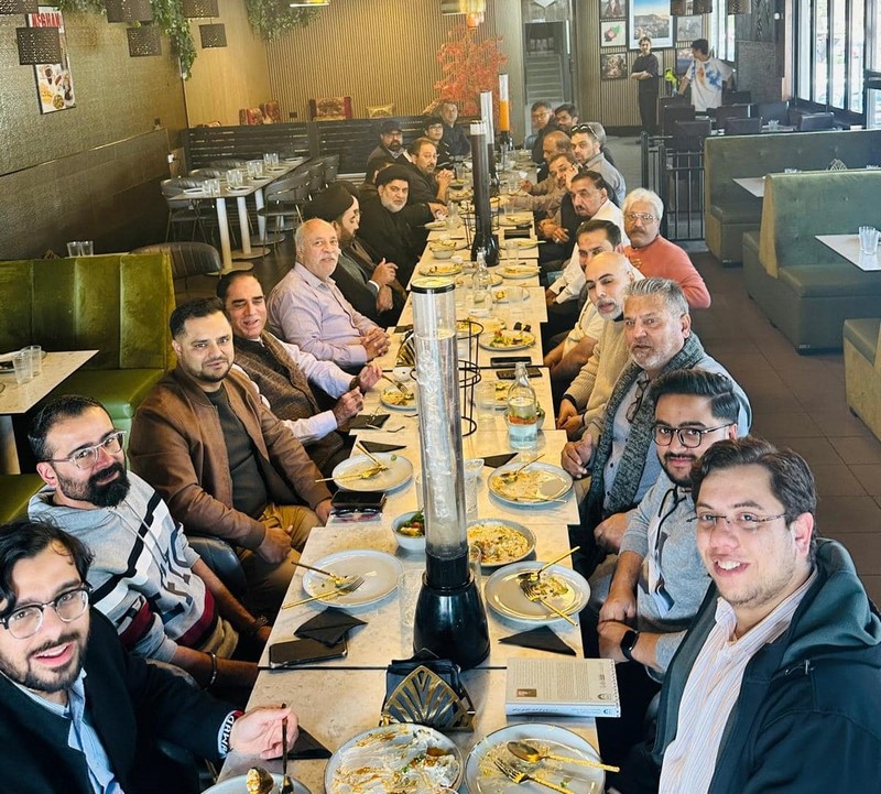 A group of people sitting at a long table with food
Description automatically generated