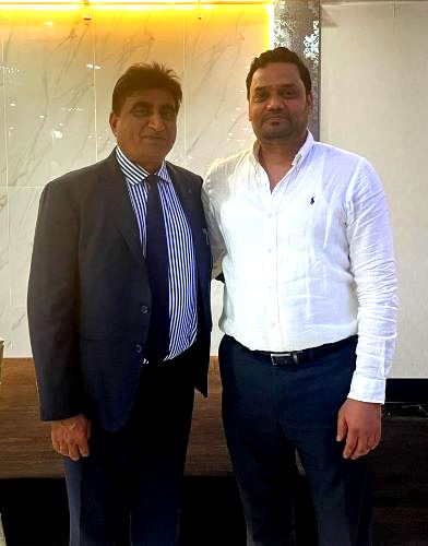 Two men standing together in a room

Description automatically generated