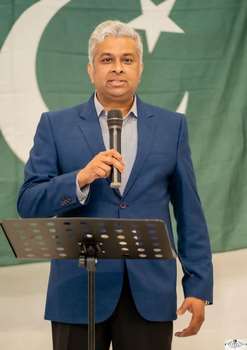 A person standing at a podium holding a microphone
Description automatically generated