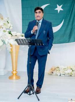A person in a suit holding a microphone
Description automatically generated