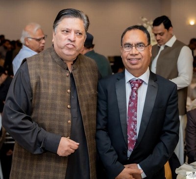 Two men standing together in a room
Description automatically generated