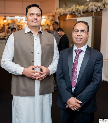 Two men standing together in a room
Description automatically generated