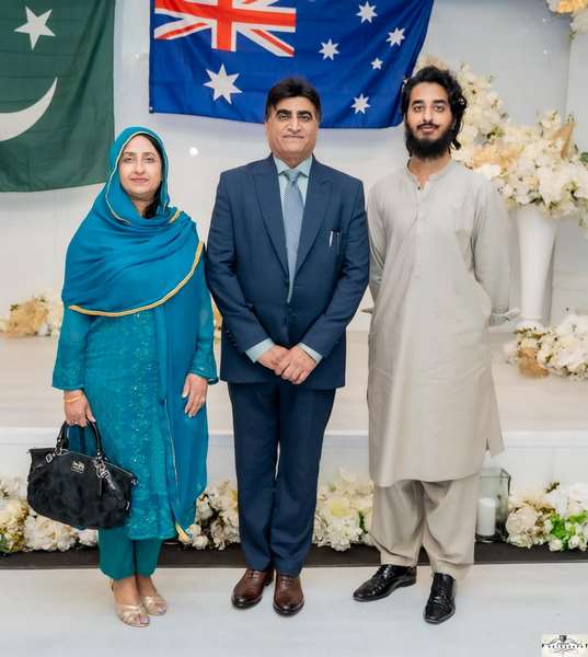 A group of people standing in front of a flag
Description automatically generated
