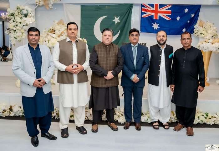 A group of men standing in front of flags
Description automatically generated