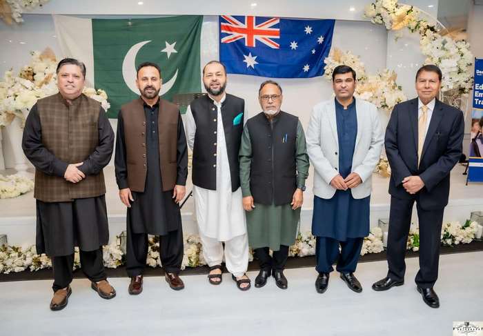 A group of men standing in front of flags
Description automatically generated