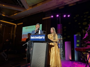A person and person standing at a podium
Description automatically generated