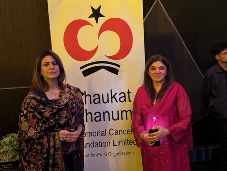 Women standing in front of a sign
Description automatically generated