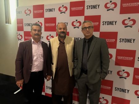 A group of men standing in front of a wall with red and white checkered walls
Description automatically generated