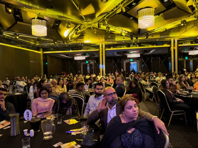 A group of people sitting at tables in a room
Description automatically generated