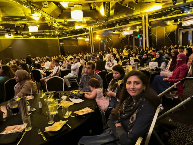 A group of people sitting at tables in a room
Description automatically generated