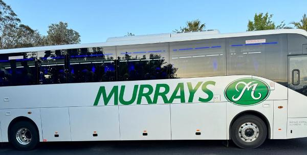 A white bus with green writing on it

Description automatically generated