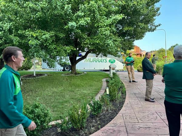 A group of people standing on a sidewalk

Description automatically generated