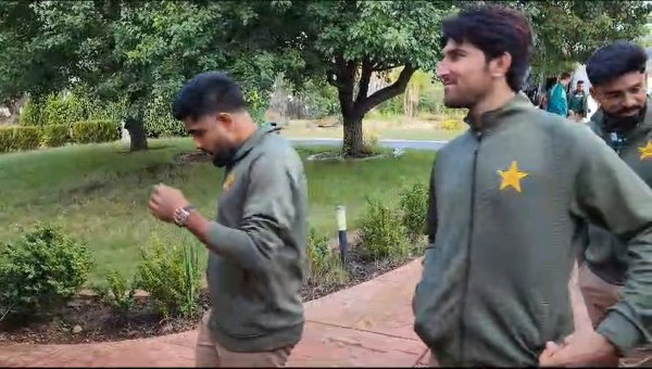 A couple of men walking on a sidewalk

Description automatically generated