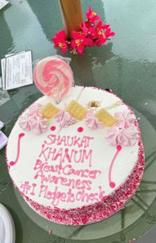 A cake with pink frosting and a lollipop on top

Description automatically generated