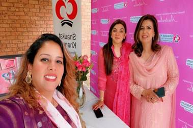 A group of women standing in front of a pink sign

Description automatically generated