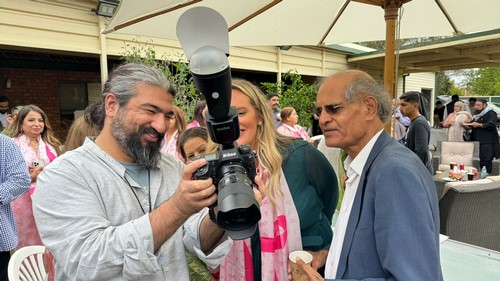 A person holding a camera with a person looking at a camera

Description automatically generated